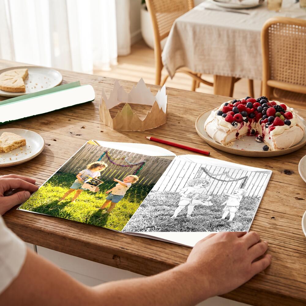 A photo on the left page and the same moment as a colouring page on the right.